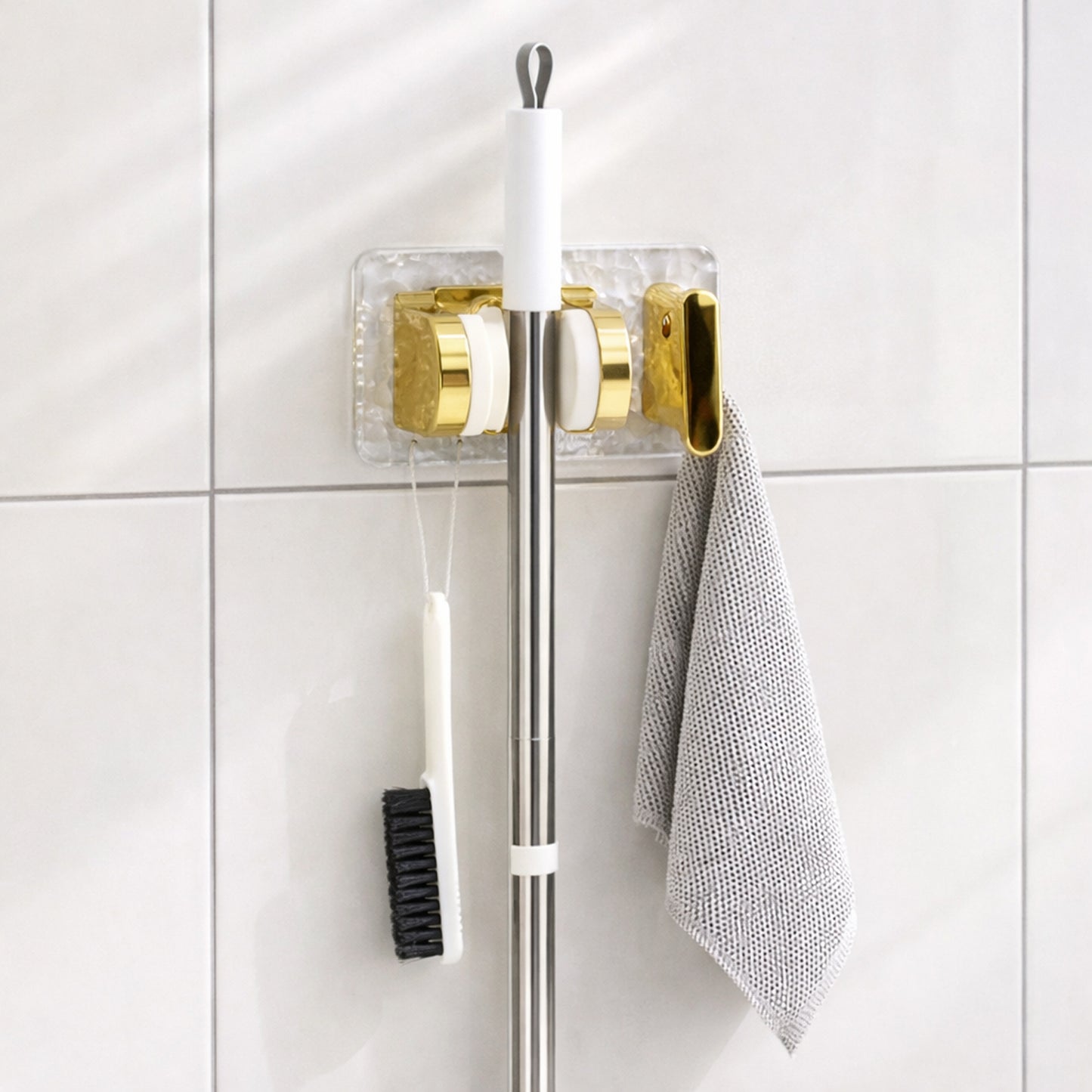 Wall mounted broom and mop holder by Wukusy with strong grip clips for secure storage, shown holding a broom and mop.