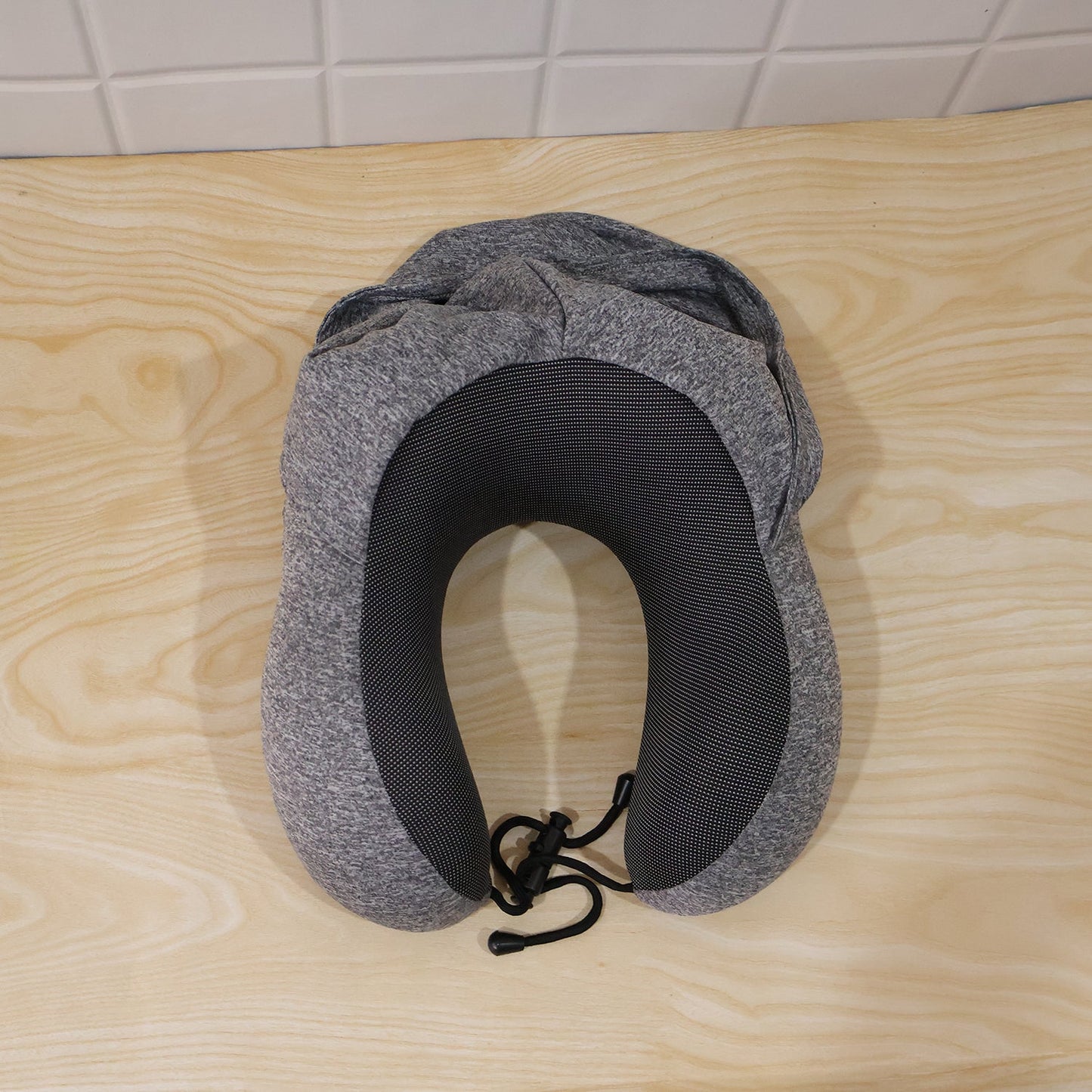 Grey U-shaped Wukusy travel hooded neck pillow with drawstring hood, designed for comfort during travel.