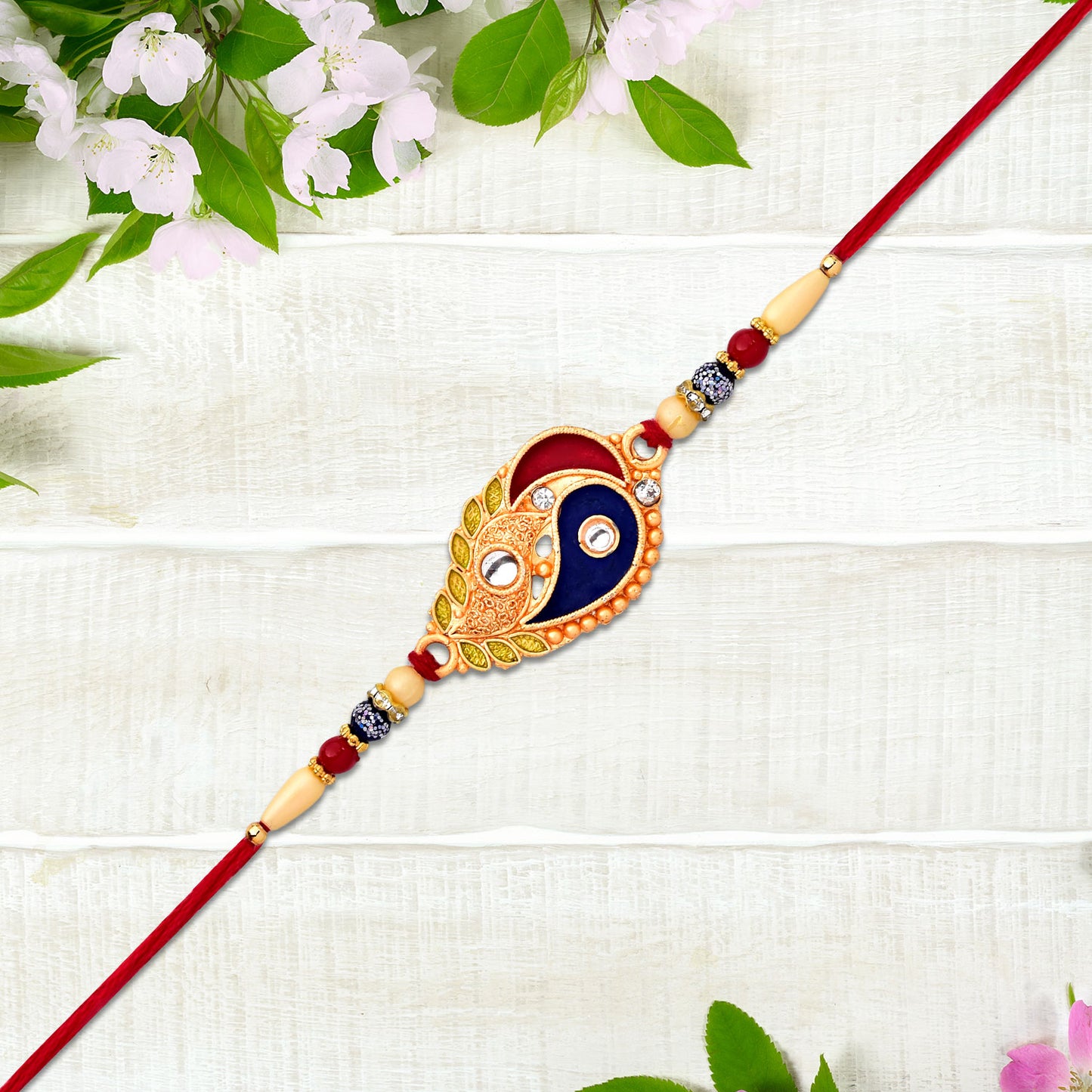 Elegant Wukusy Rakhi with enamel paisley design and gold-tone embellishments, showcasing intricate craftsmanship.