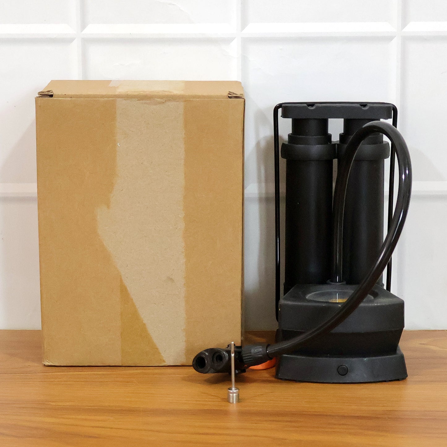 Wukusy double cylinder foot air pump with two nozzles for inflating tires, sports balls, and inflatable items, shown in use.