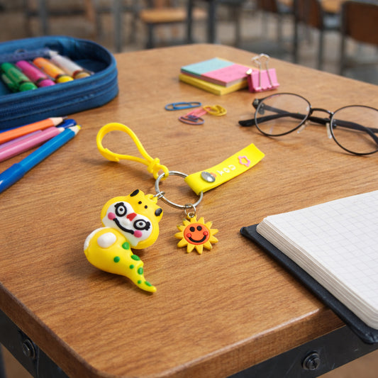 Cute cartoon dinosaur keychain with strap and decorative charm, featuring vibrant colors and detailed dinosaur design.