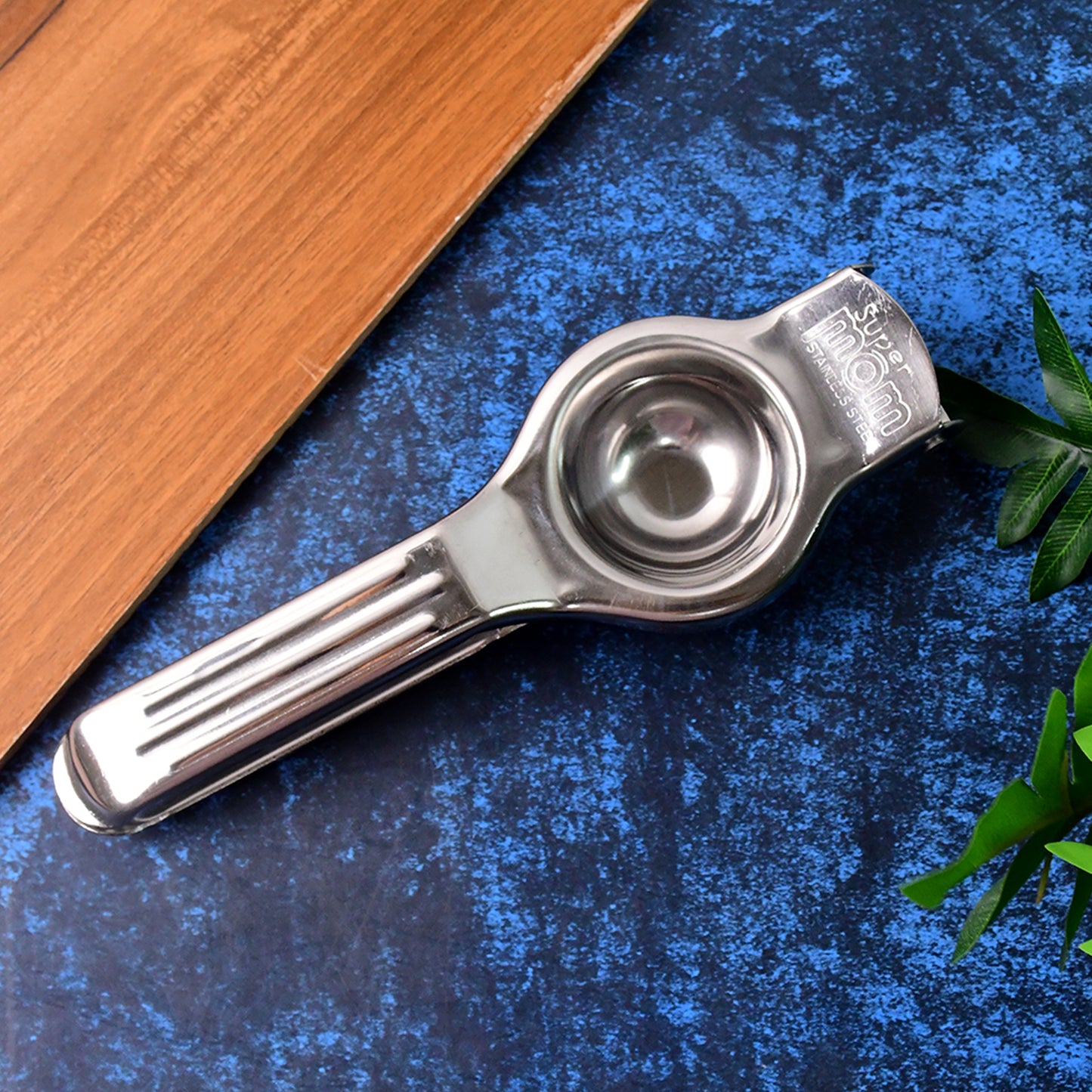 Wukusy Supermom 2-in-1 stainless steel lemon squeezer with built-in bottle opener in a home kitchen setting.