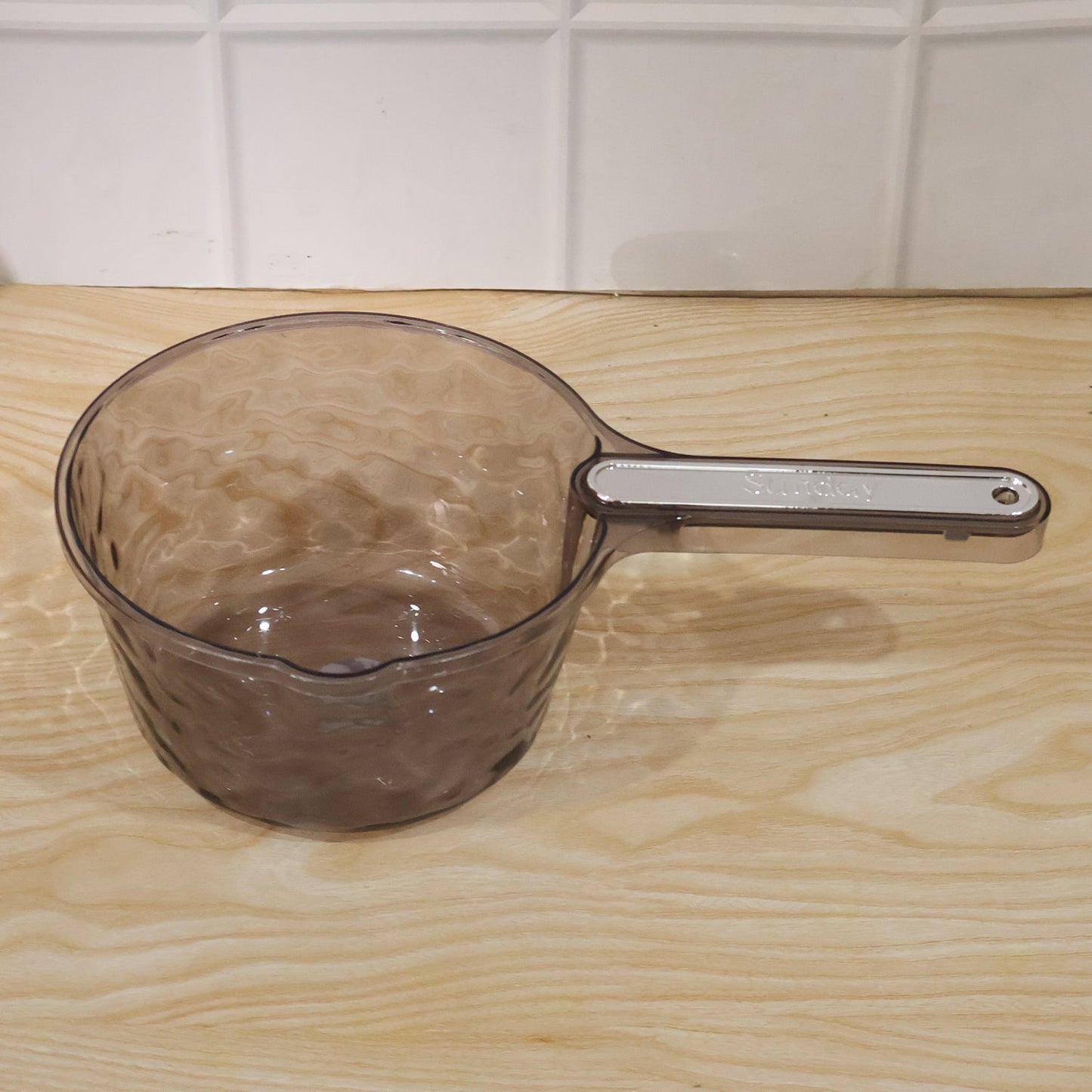 Wukusy transparent plastic water dipper scoop with handle, designed for bathroom use, shown with water inside the scoop.