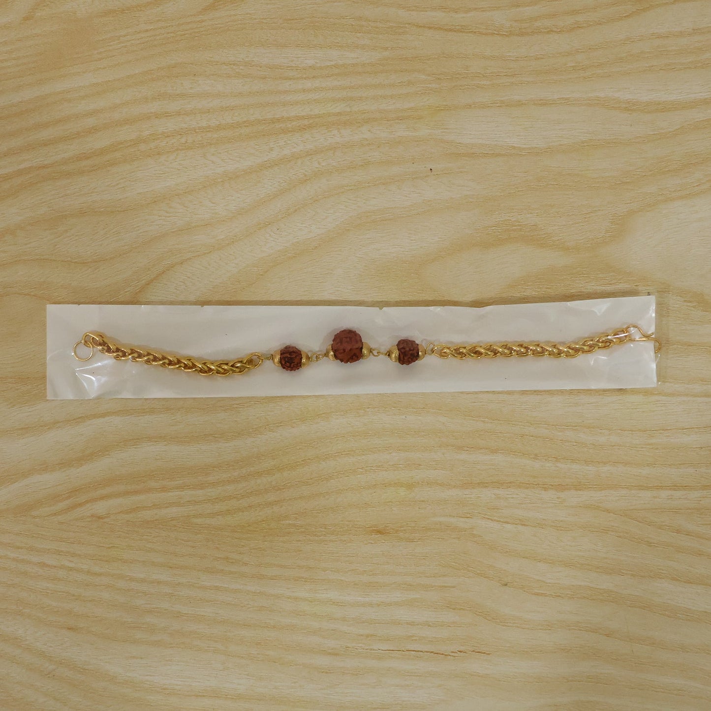 Gold-plated Rudraksha bead Rakhi with chain for brother, featuring intricate design and traditional craftsmanship.