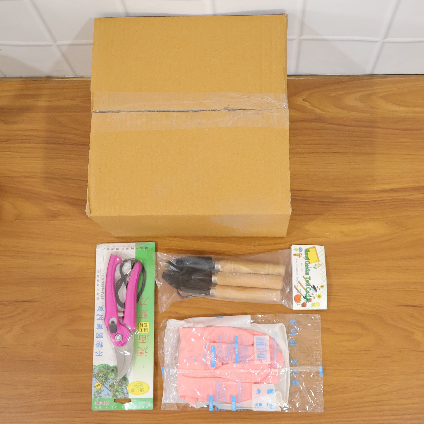 Wukusy complete gardening tool kit with trowel, pruning shears, weeder, and gloves on a wooden work surface for gardening tasks.