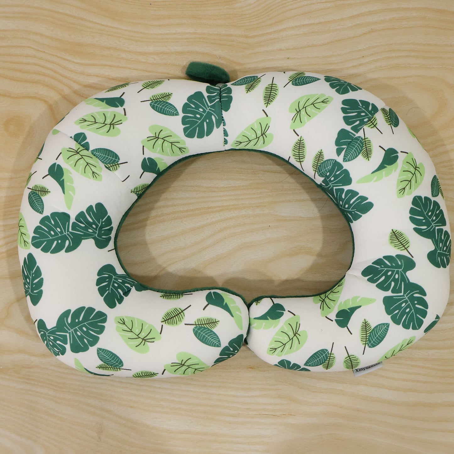 Green leaf print U-shaped travel neck pillow by Wukusy, soft head support for comfortable travel rest.