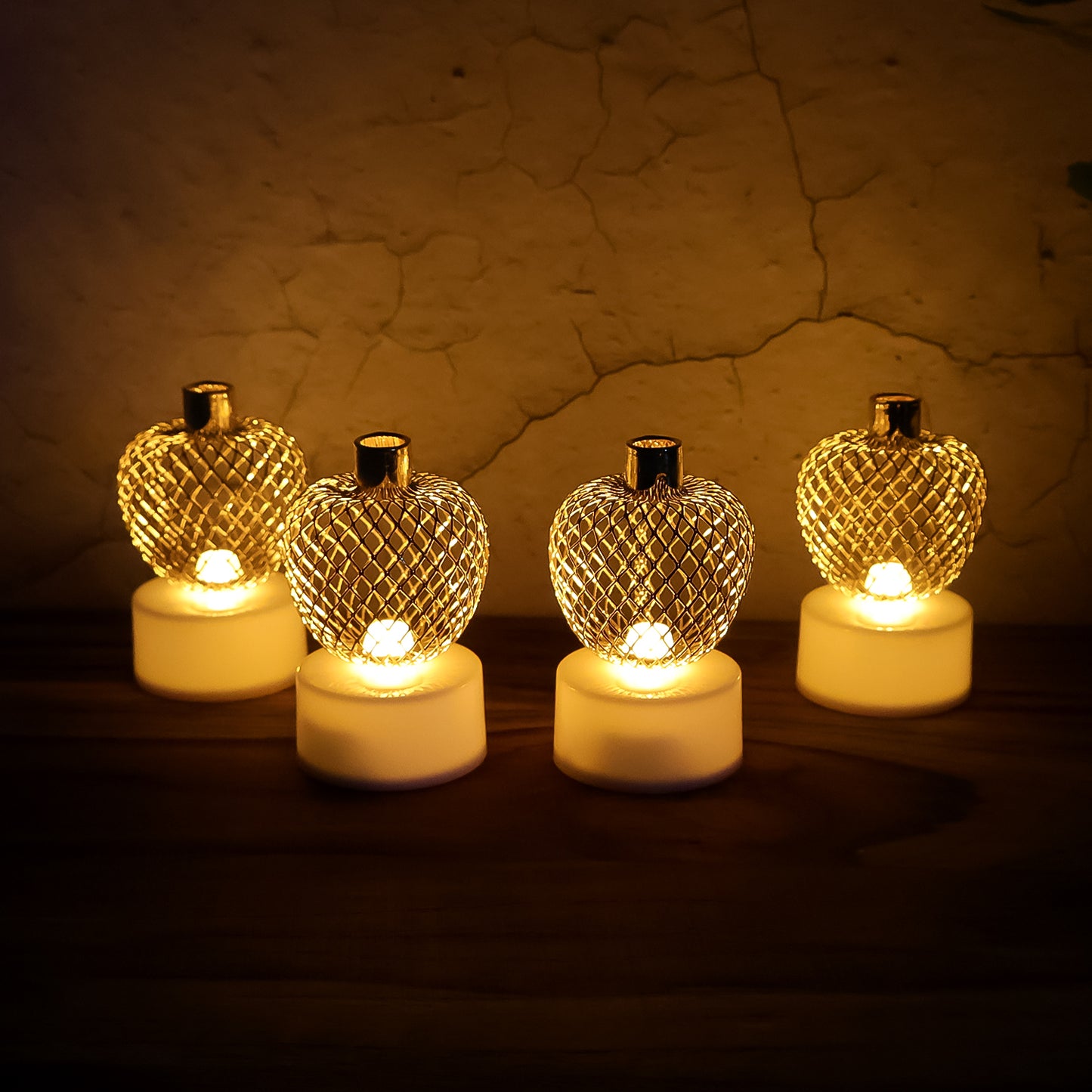 Set of four Wukusy decorative apple-shaped LED tealight candles for home decor, featuring warm, flickering light in a natural setting.