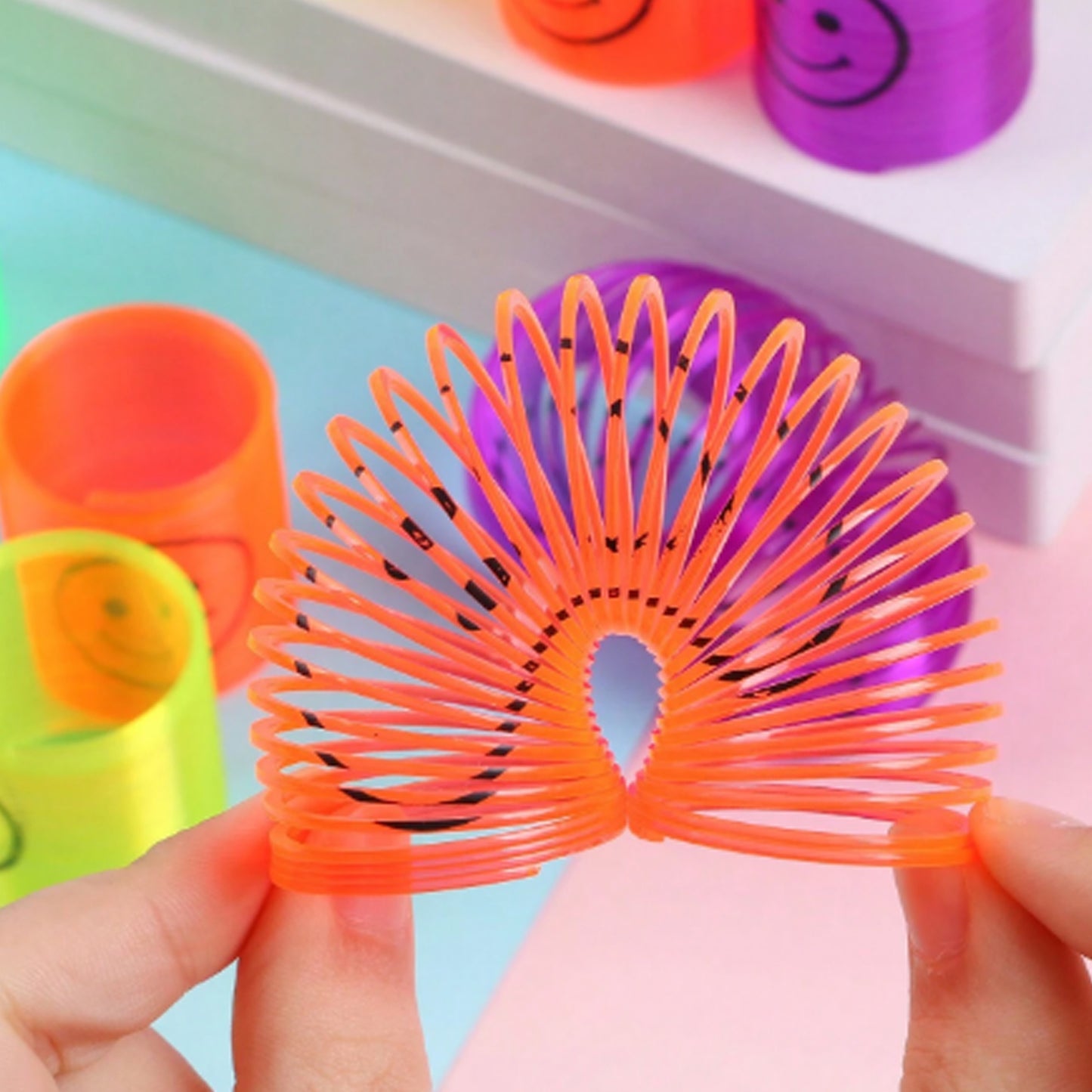 Set of 12 multicolor Wukusy spring toys featuring smiley faces, compact and portable for kids' birthdays and fun play.