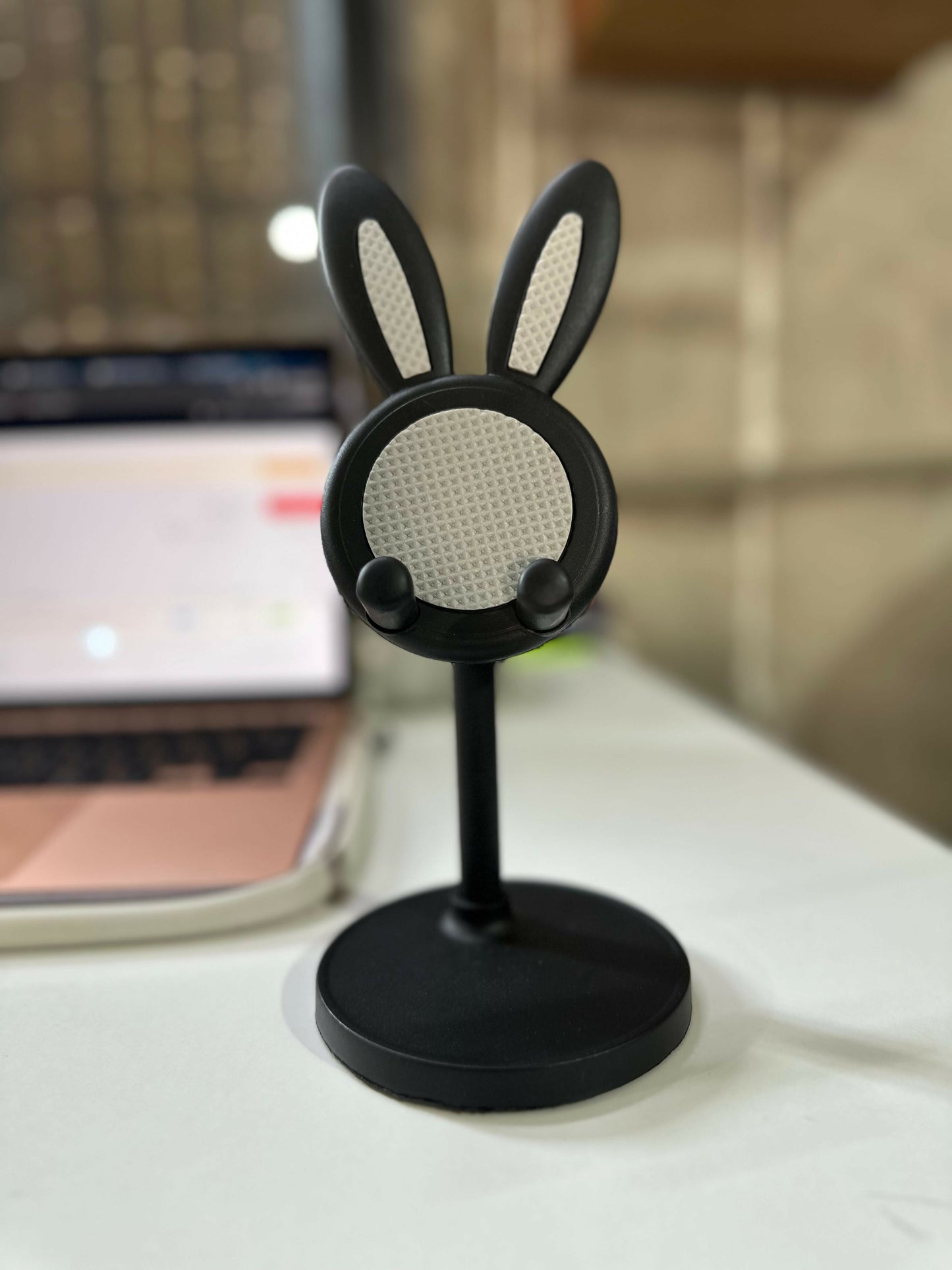 Wukusy cute bunny mobile stand holder on a desk, designed for kids' study tables, with a colorful bunny figure for holding phones.