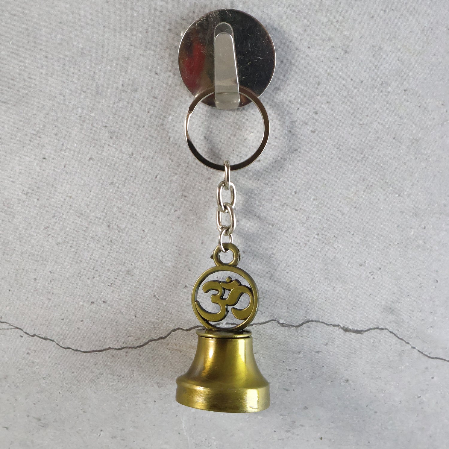 Wukusy Om Symbol temple bell metal keychain, travel accessory with Om design and small bell, hanging on a keyring.