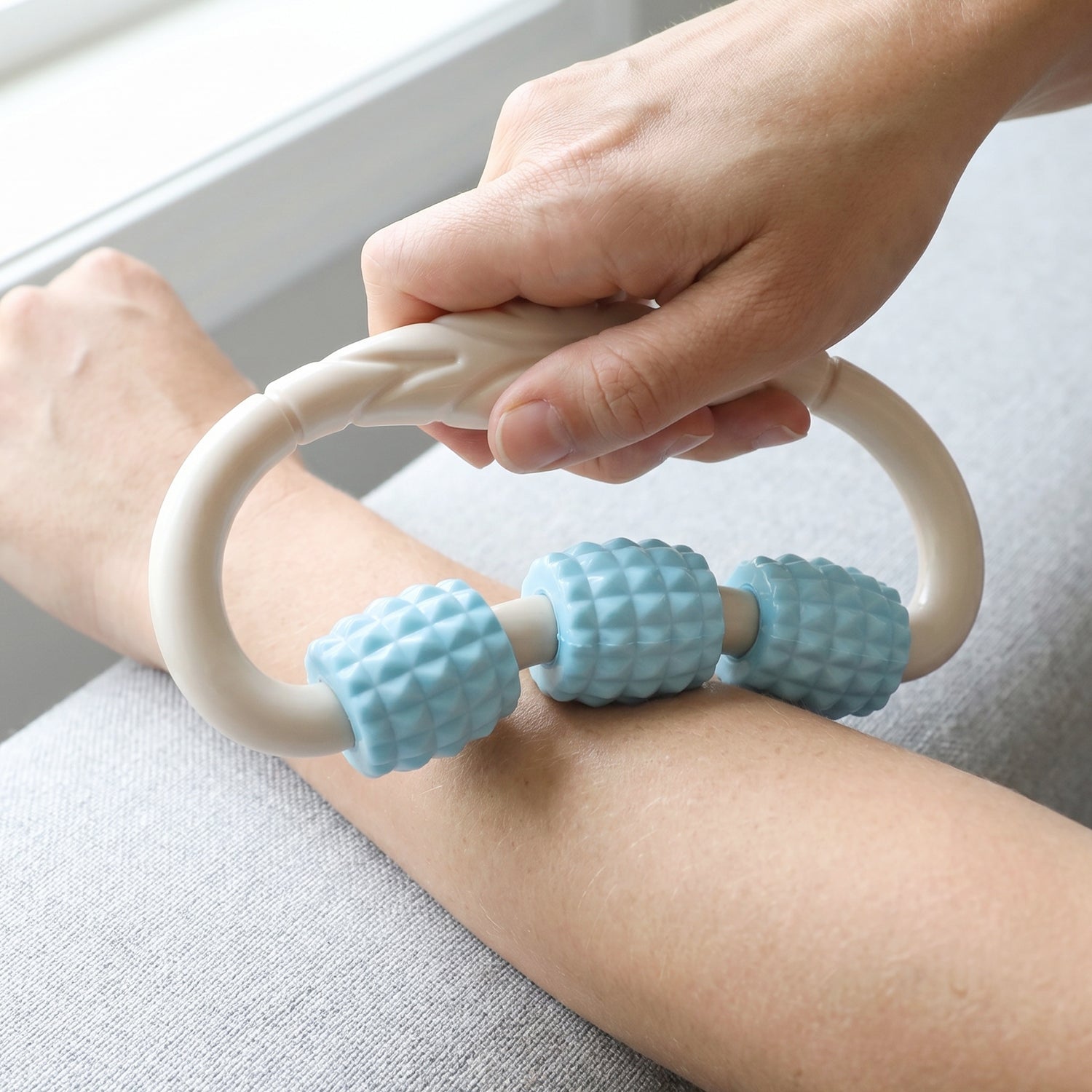 Wukusy handheld 3 roller body massager ring for muscle relaxation on arms and legs, showing the textured rollers and compact design