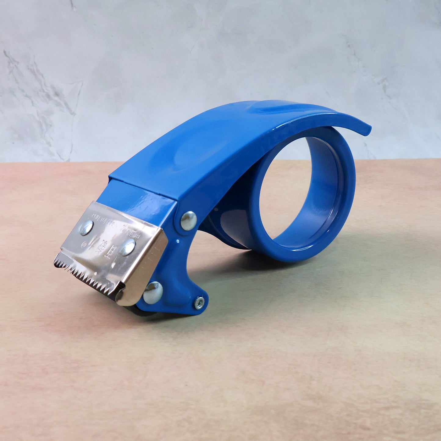 Wukusy heavy-duty tape dispenser cutter with ergonomic handle and metal cutting blade, shown on a flat surface.