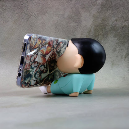 Wukusy cute cartoon figurine mobile phone stand on a desk, featuring colorful, whimsical character design for holding a smartphone.