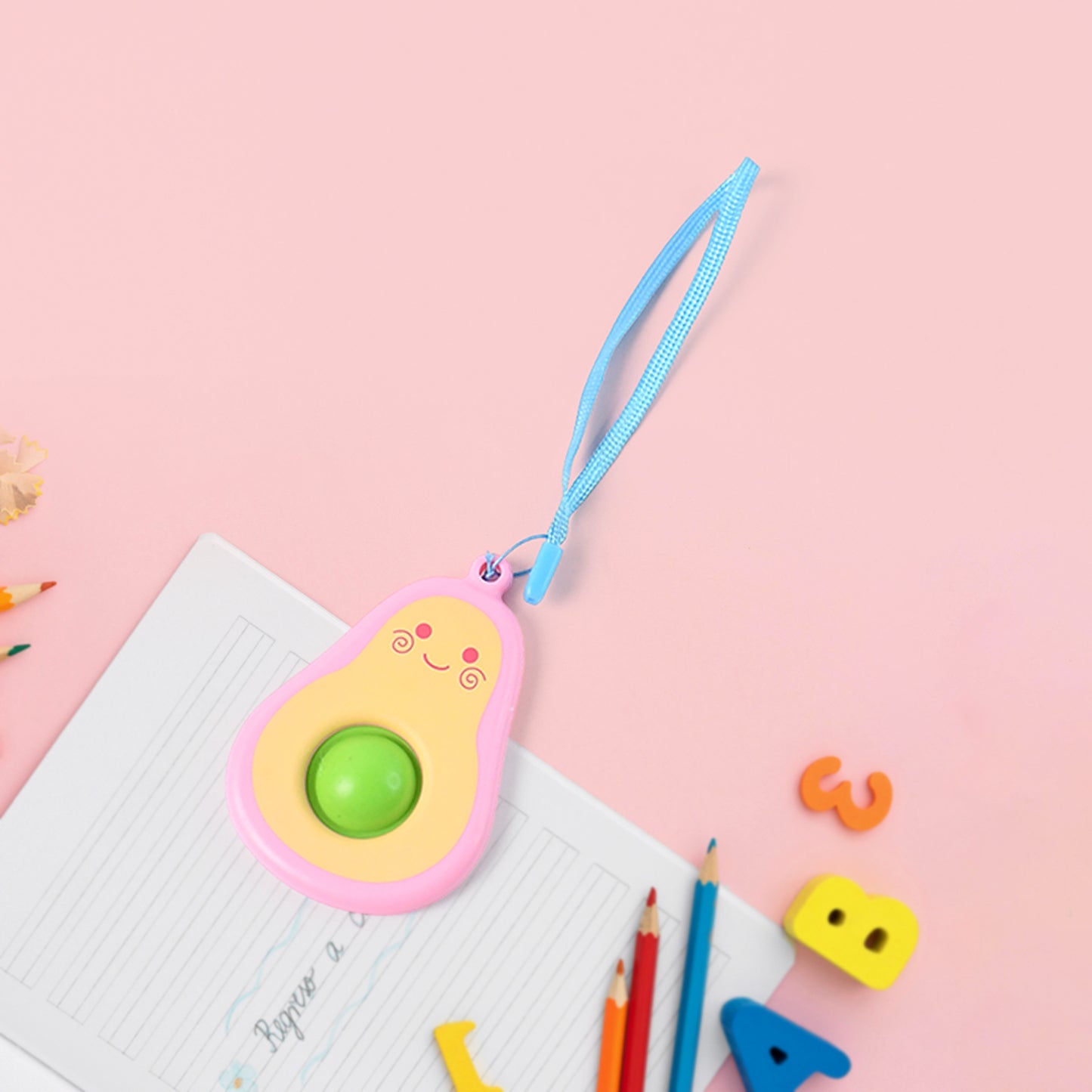 Cute avocado-shaped mini push pop keychain toy with strap from Wukusy, featuring bright green and textured avocado design.