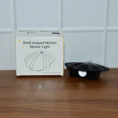 Wukusy shell-shaped motion sensor night light as a home decor accessory, with a sleek design and soft illumination in a cozy setting.