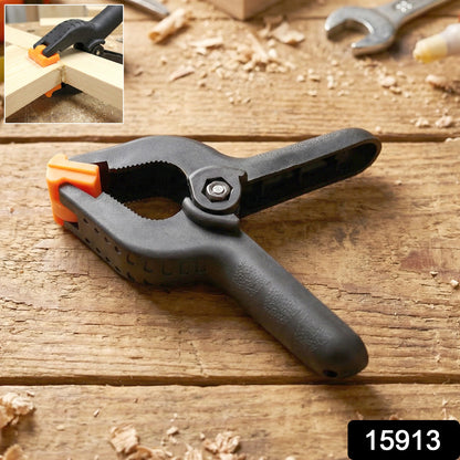 Heavy-duty Wukusy spring clamp holding materials, showcasing its strong metal jaws and ergonomic handle for secure grip.