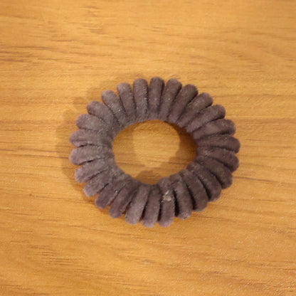 Soft stretchable telephone wire style hair band by Wukusy, shown in a close-up of the flexible, coil design on a plain background.