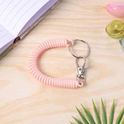 Wukusy elastic spiral coil keychain bracelet with metal key ring and clip hook, shown coiled on a white background