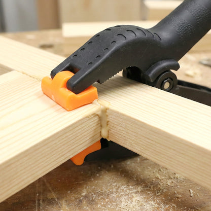 Heavy-duty Wukusy spring clamp holding materials securely, featuring strong metal jaws and red plastic handles.