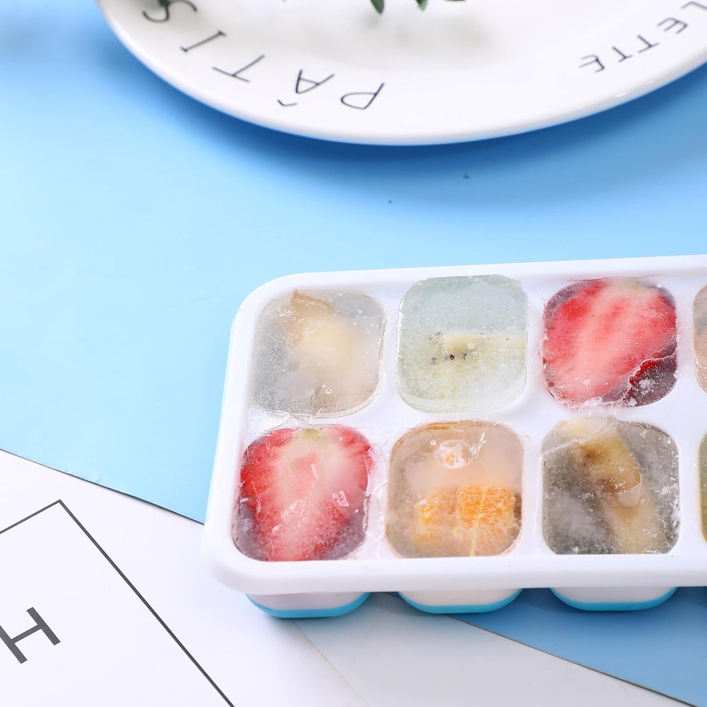 Blue plastic ice cube tray with lid, 14-grid multipurpose ice mold from Wukusy, showing the tray filled with ice cubes.