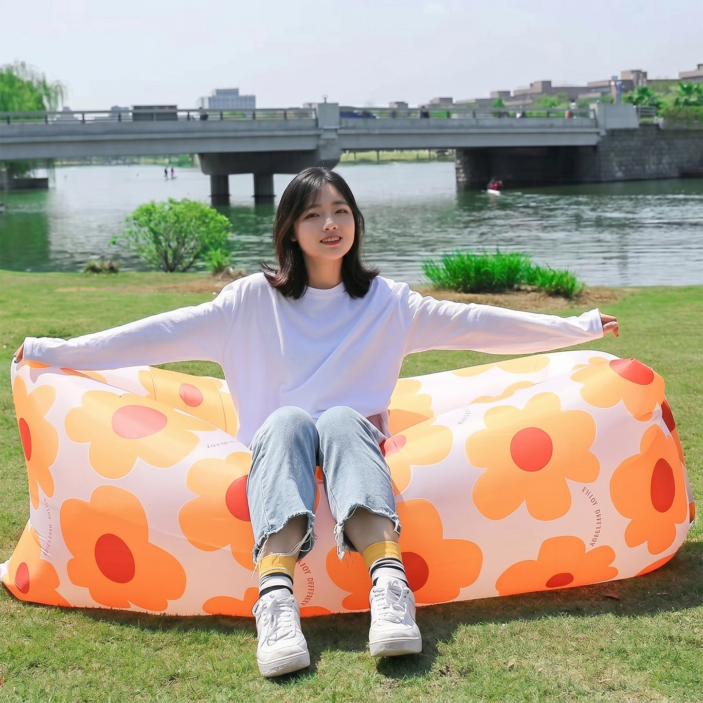 Wukusy portable inflatable air lounger sofa for outdoor beach, garden, and travel, shown inflated on grass with open sky background.