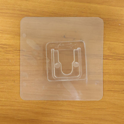 Transparent self-adhesive wall hook by Wukusy mounted on a wall, showing its clear design and adhesive backing for easy installation.