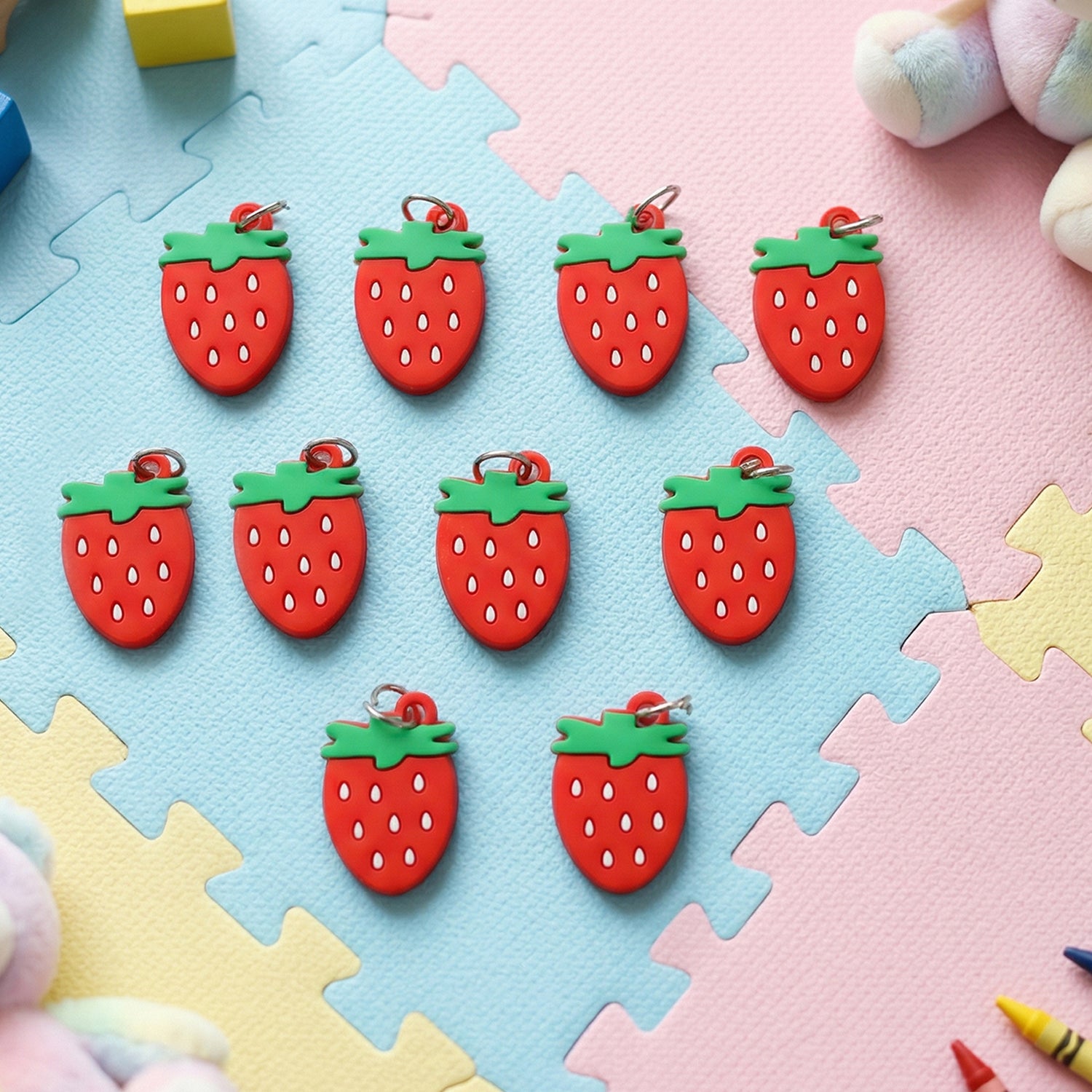Set of 10 Wukusy strawberry design bag charm keychains with colorful, playful fruit motifs on a white background.