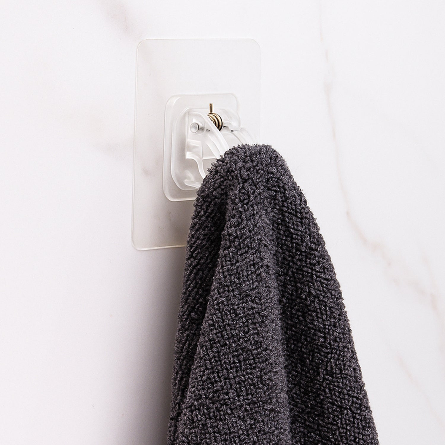 Transparent self-adhesive wall hook holder clip by Wukusy attached to a wall for hanging lightweight items.