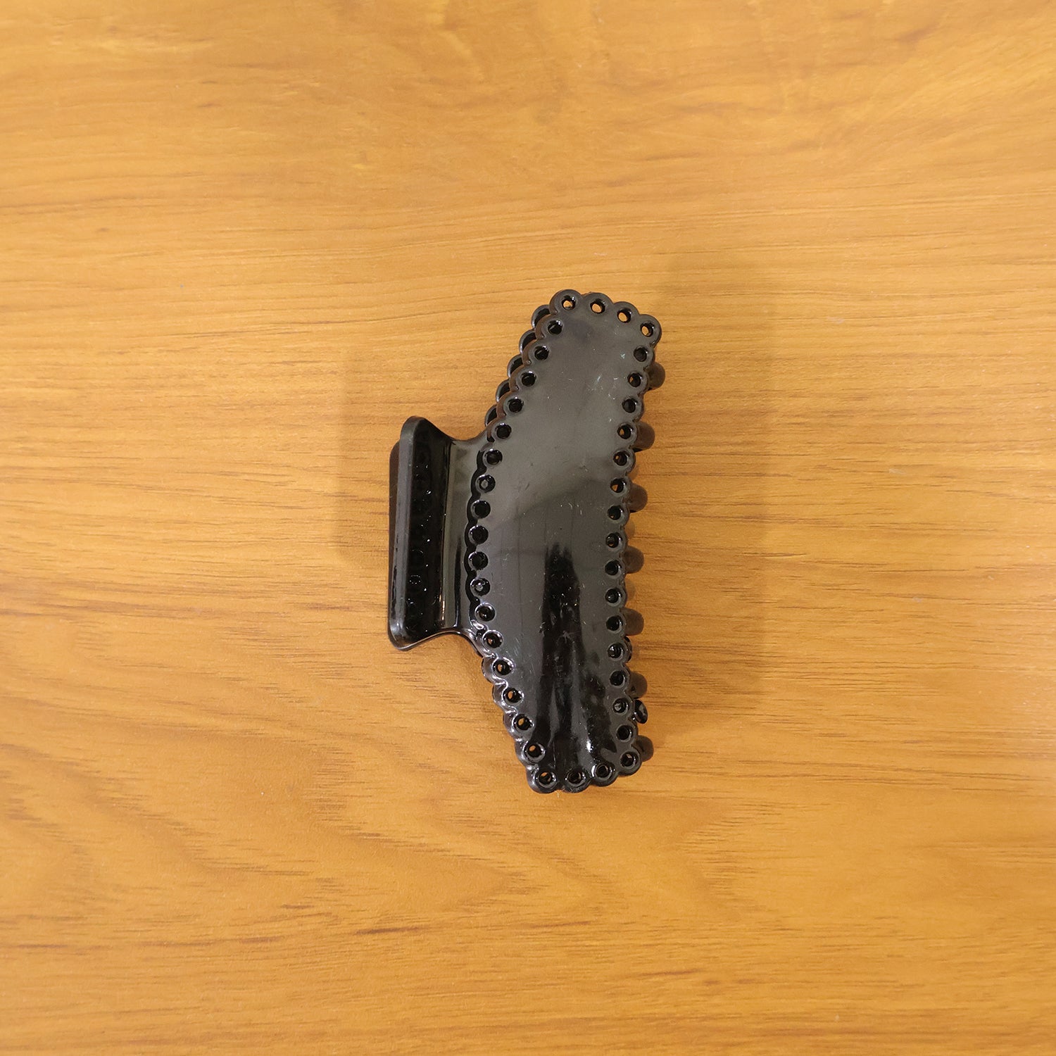 Black hair claw clip by Wukusy, elegant and functional, shown holding hair in a sleek style.