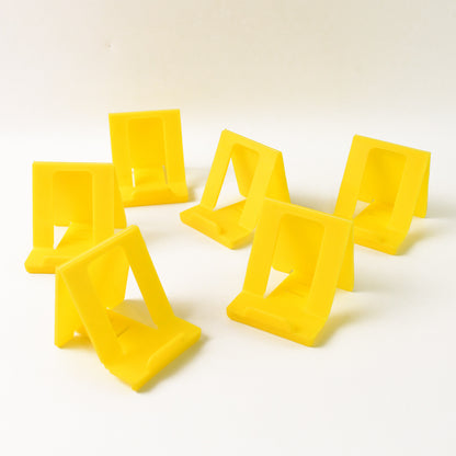 Six Wukusy adjustable foldable plastic mobile phone stands in mixed colors, shown folded and extended for hands-free viewing.