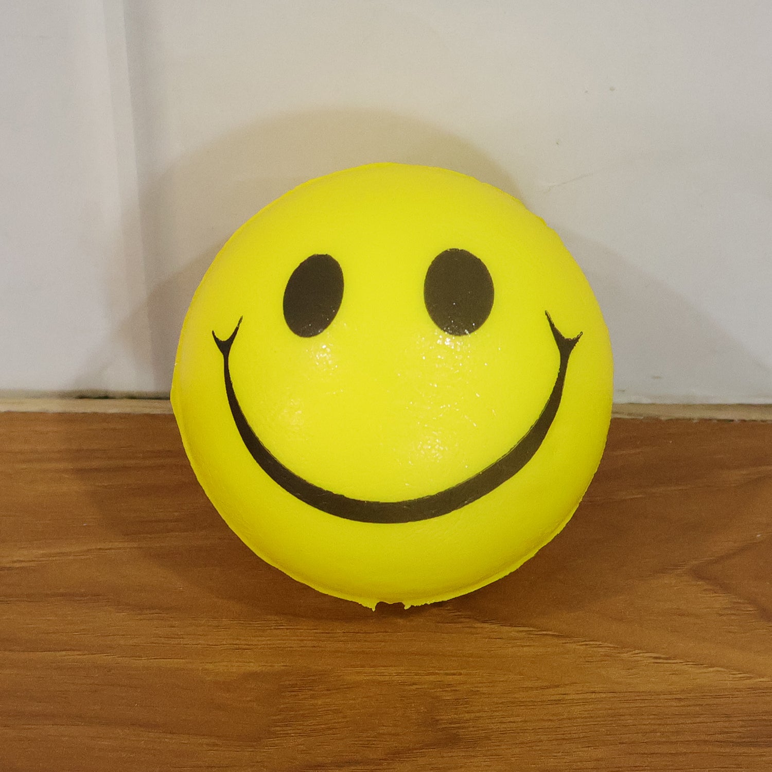 Soft foam smiley toy ball by Wukusy, bright yellow with a cheerful smile, perfect for play and sensory fun for children.