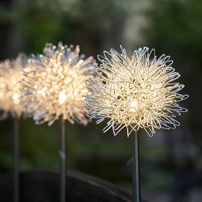 Two Wukusy solar-powered dandelion garden lights illuminating a garden at dusk with a soft glow
