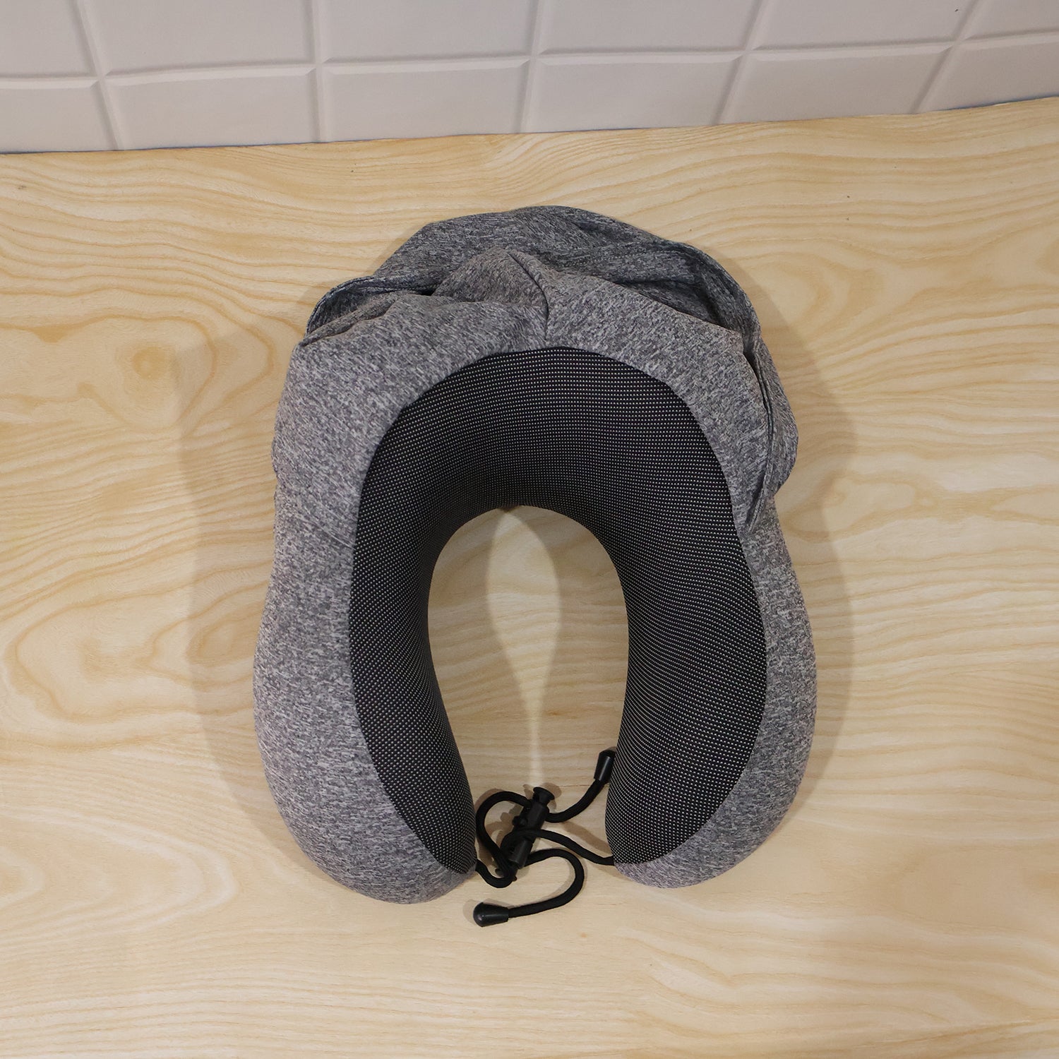 Grey U-shaped Wukusy travel hooded neck pillow with drawstring hood, designed for comfort during travel.