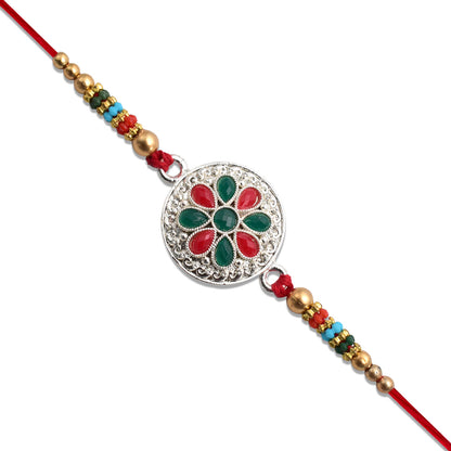 Silver plated floral Rakhi with red and green stones, featuring intricate design and elegant craftsmanship by Wukusy.