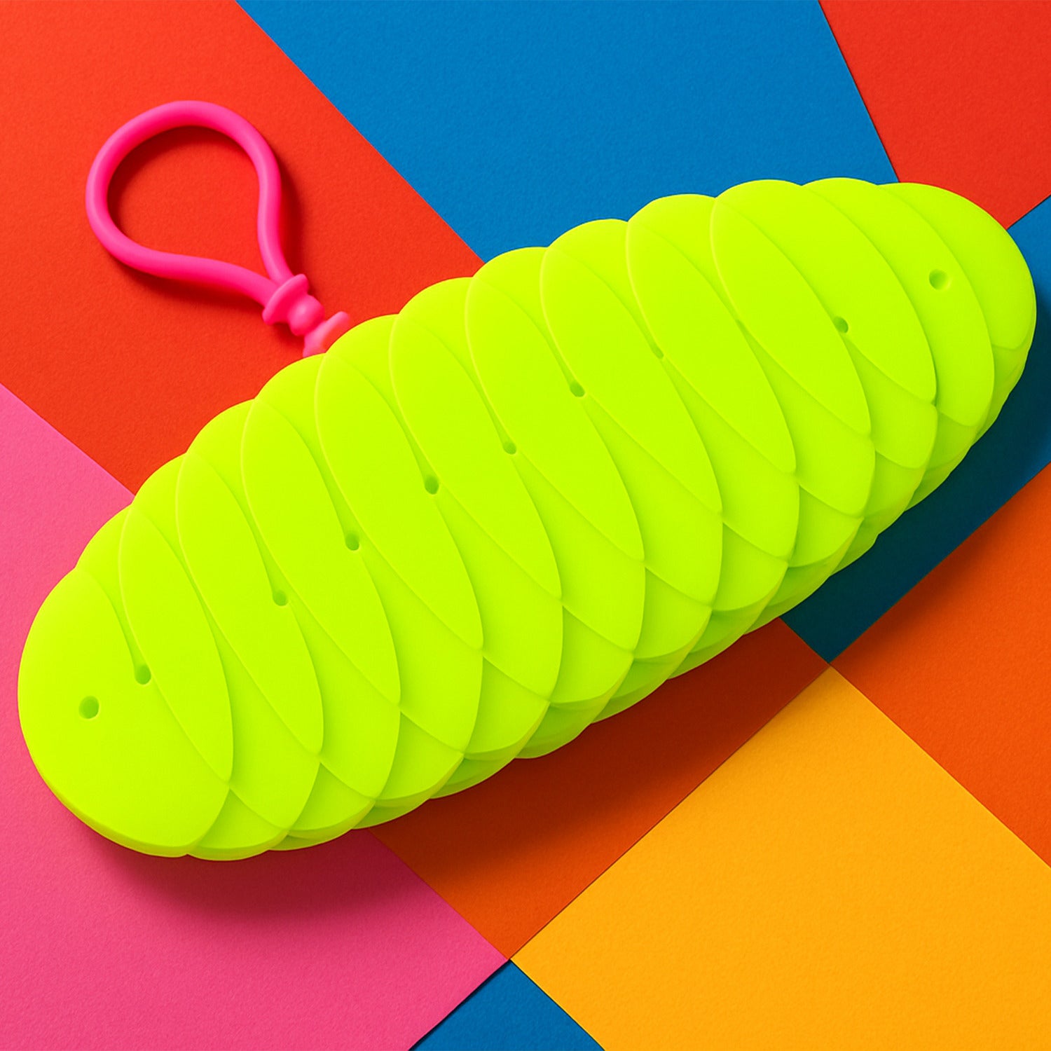 Flexible plastic worm fidget toy by Wukusy, shown in green with multiple segments, designed for stress relief and sensory play.
