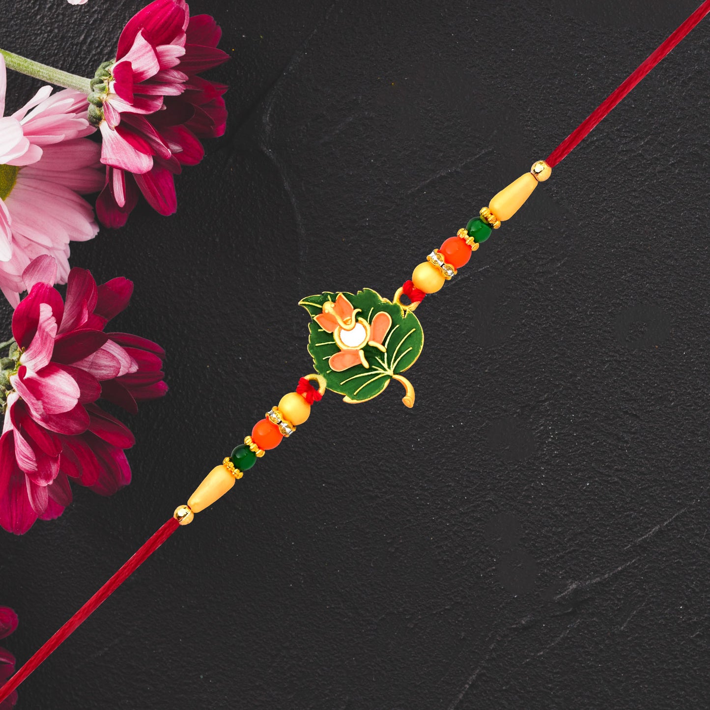 Green Tulsi leaf Rakhi with orange enamel flower and beaded thread, traditional Wukusy fashion accessory for festive occasions.