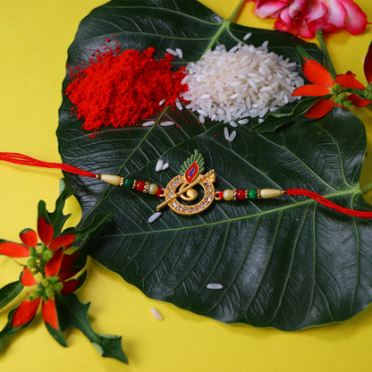 Wukusy Krishna Flute Rakhi with stone-studded peacock feather design, featuring intricate fashion embroidery and vibrant colors.