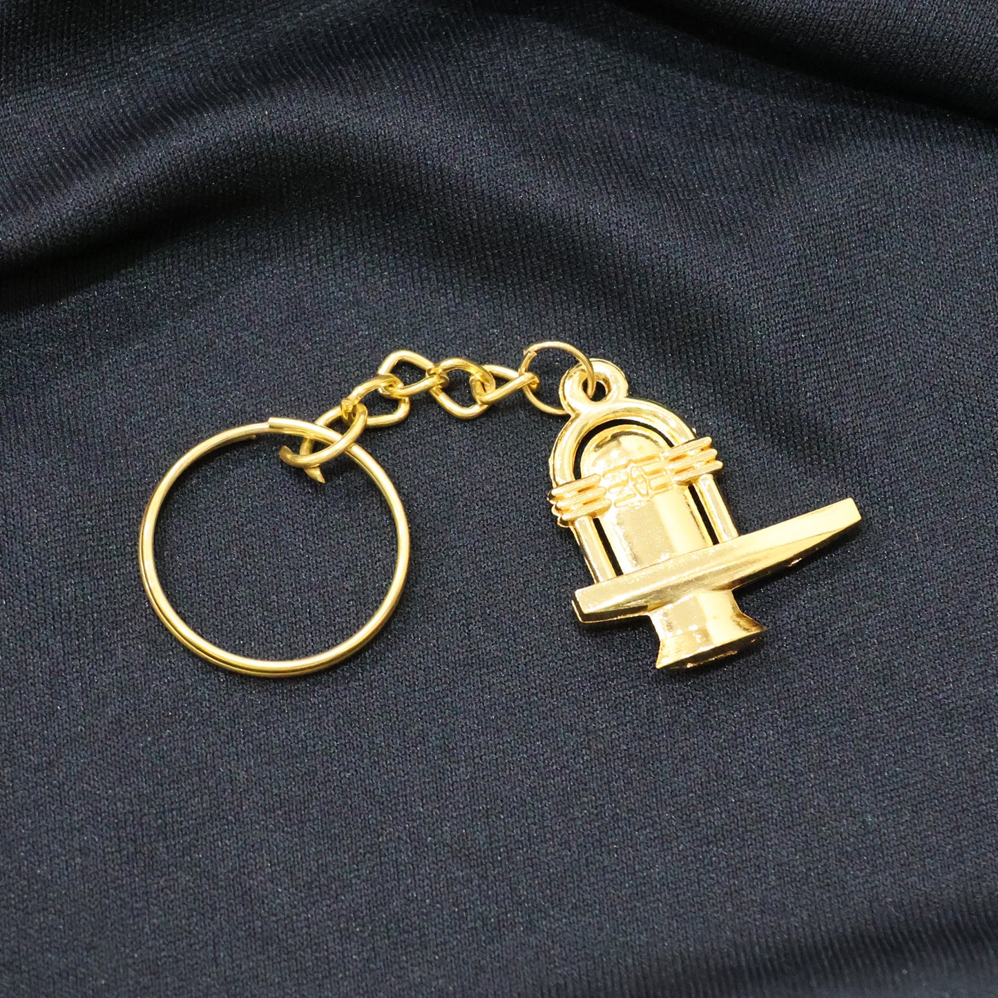 Golden metal Shivling keychain from Wukusy showing detailed Shivling design on a small, decorative keychain.