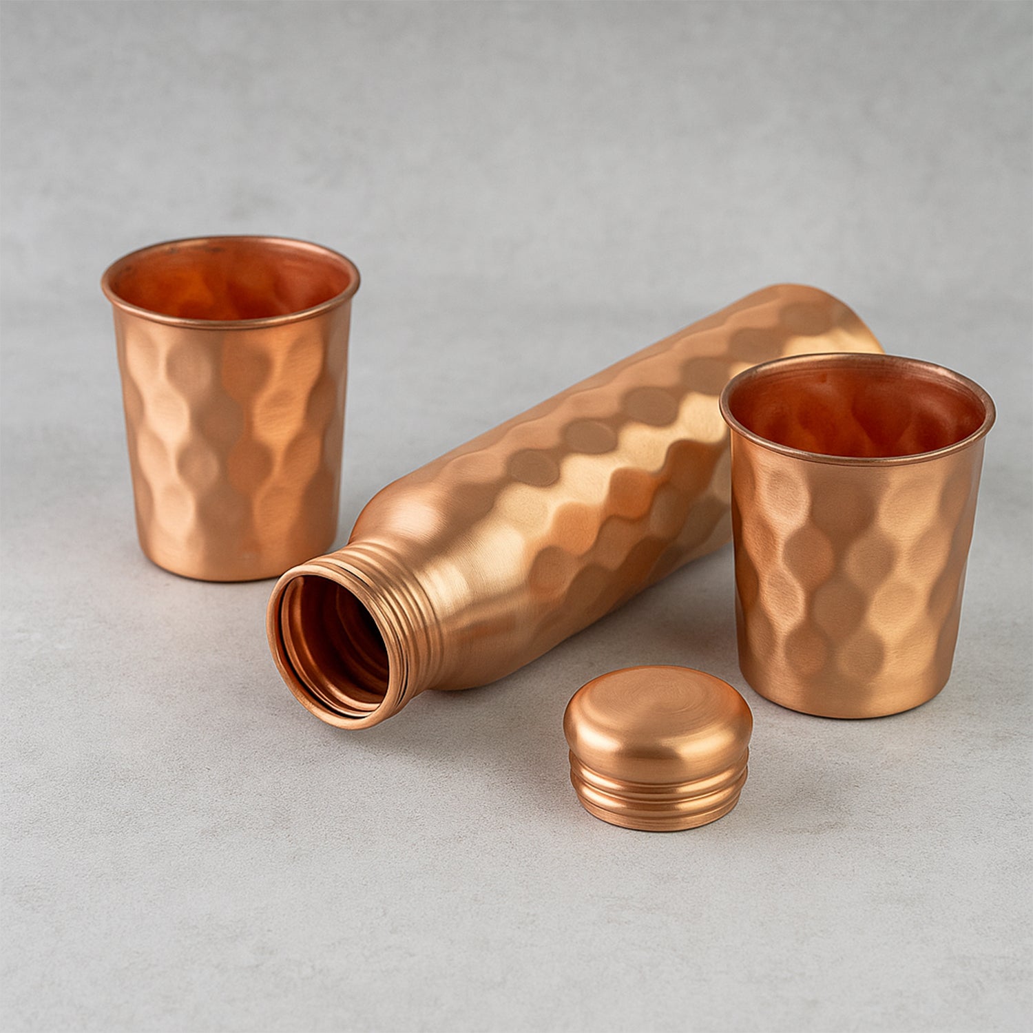Diamond cut copper water bottle with two glasses and gift box from Wukusy, showcasing the elegant design and shiny finish.