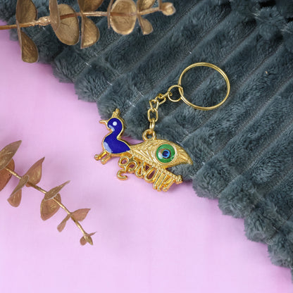 Golden Krishna peacock design keychain from Wukusy with intricate peacock and Krishna motifs, featuring a shiny finish.