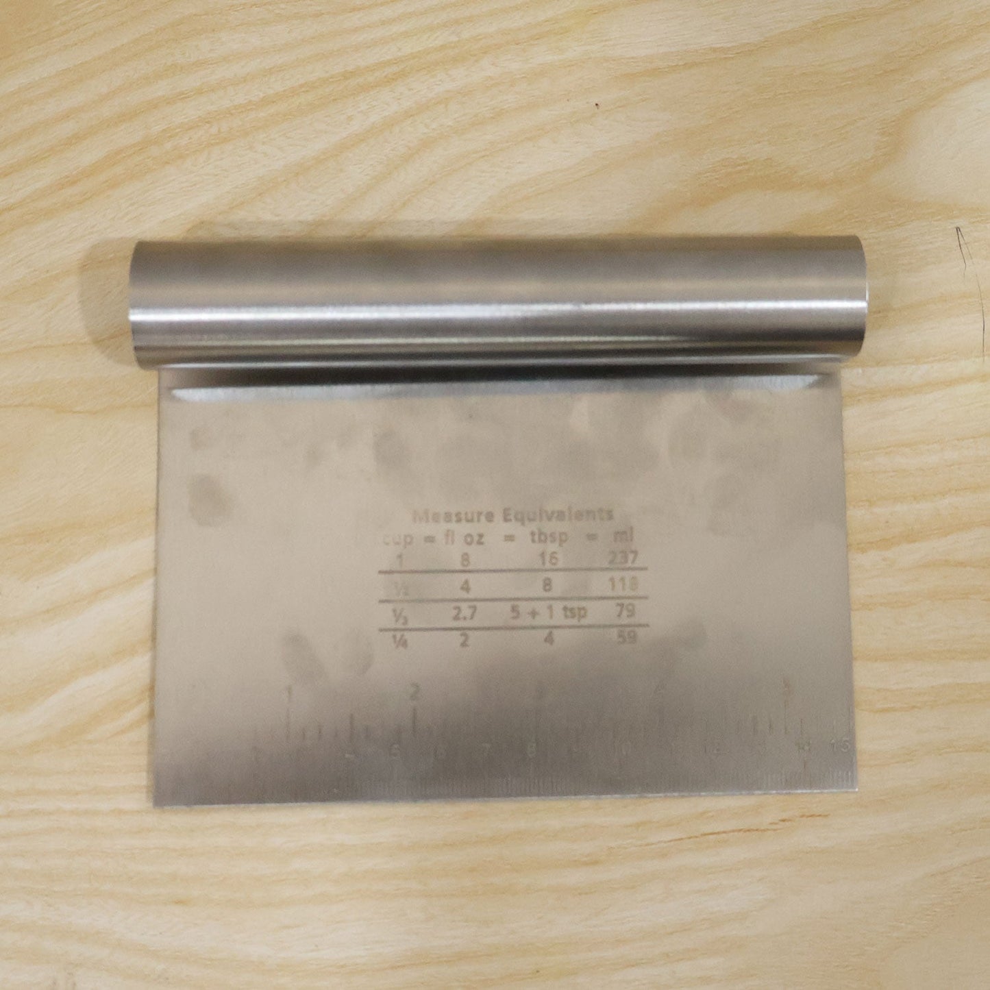 Small stainless steel dough scraper cutter with scale, 15x12 cm, by Wukusy, showing the tool with measurement markings.