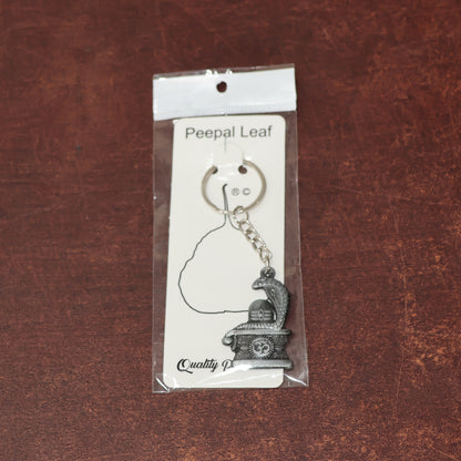 Silver Shivling keychain with snake design by Wukusy, featuring intricate details on a small, decorative jewelry accessory.