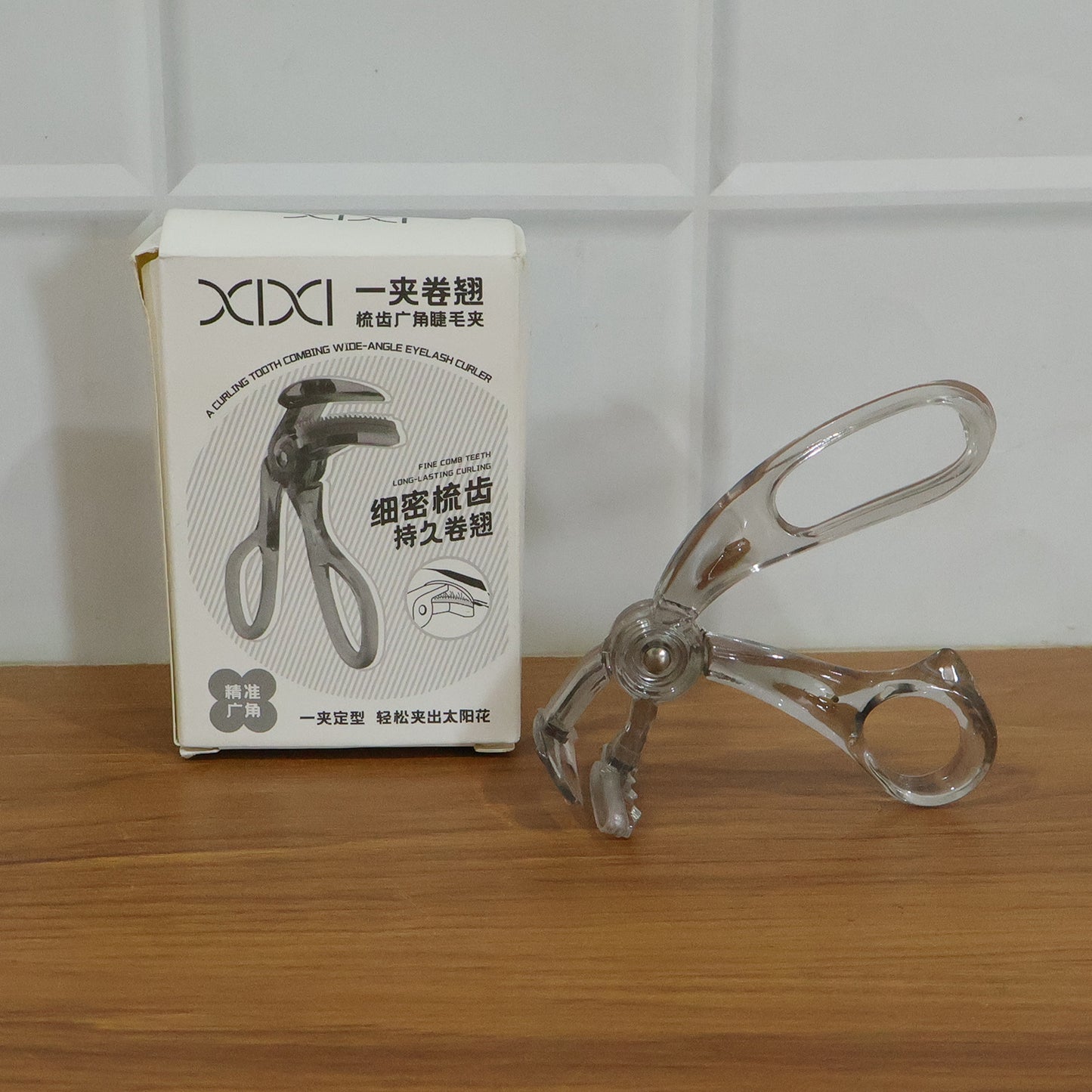 Wukusy classic plastic eyelash curler with black handle and metal clamp for curling eyelashes, close-up view.