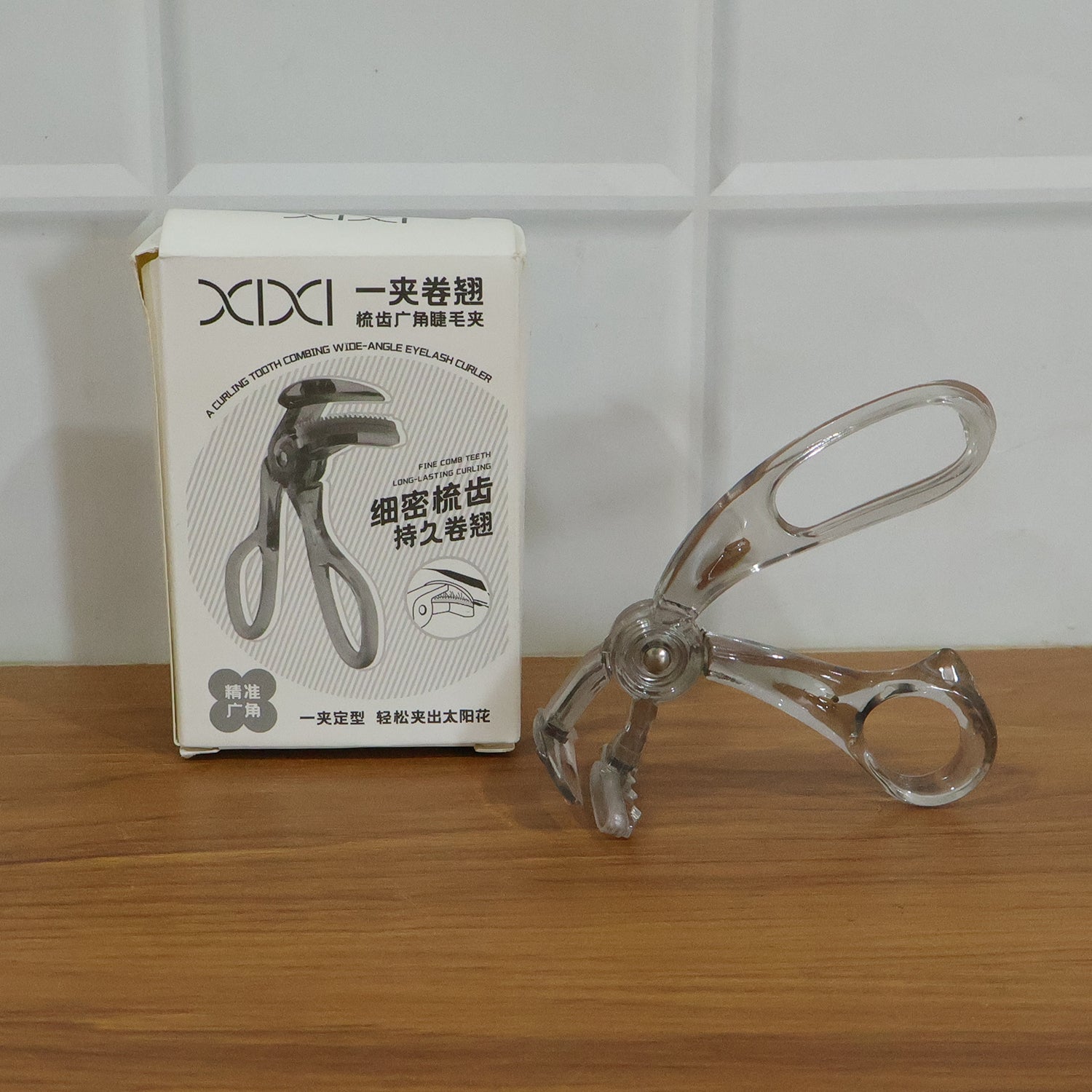 Wukusy classic plastic eyelash curler with black handle and metal clamp for curling eyelashes, close-up view.