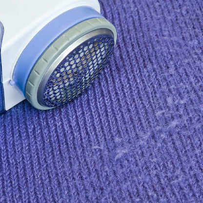 Wukusy Creative Mind lint remover for wool sweaters, blankets, and jackets, showing the handheld device on fabric.