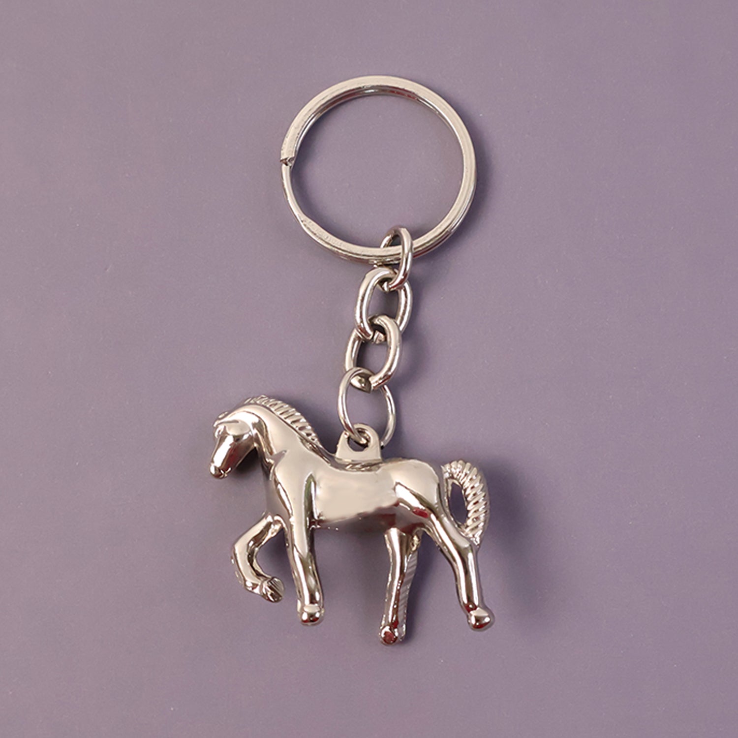 Shiny metallic horse-shaped keychain by Wukusy with a sleek finish, hanging from a keyring.