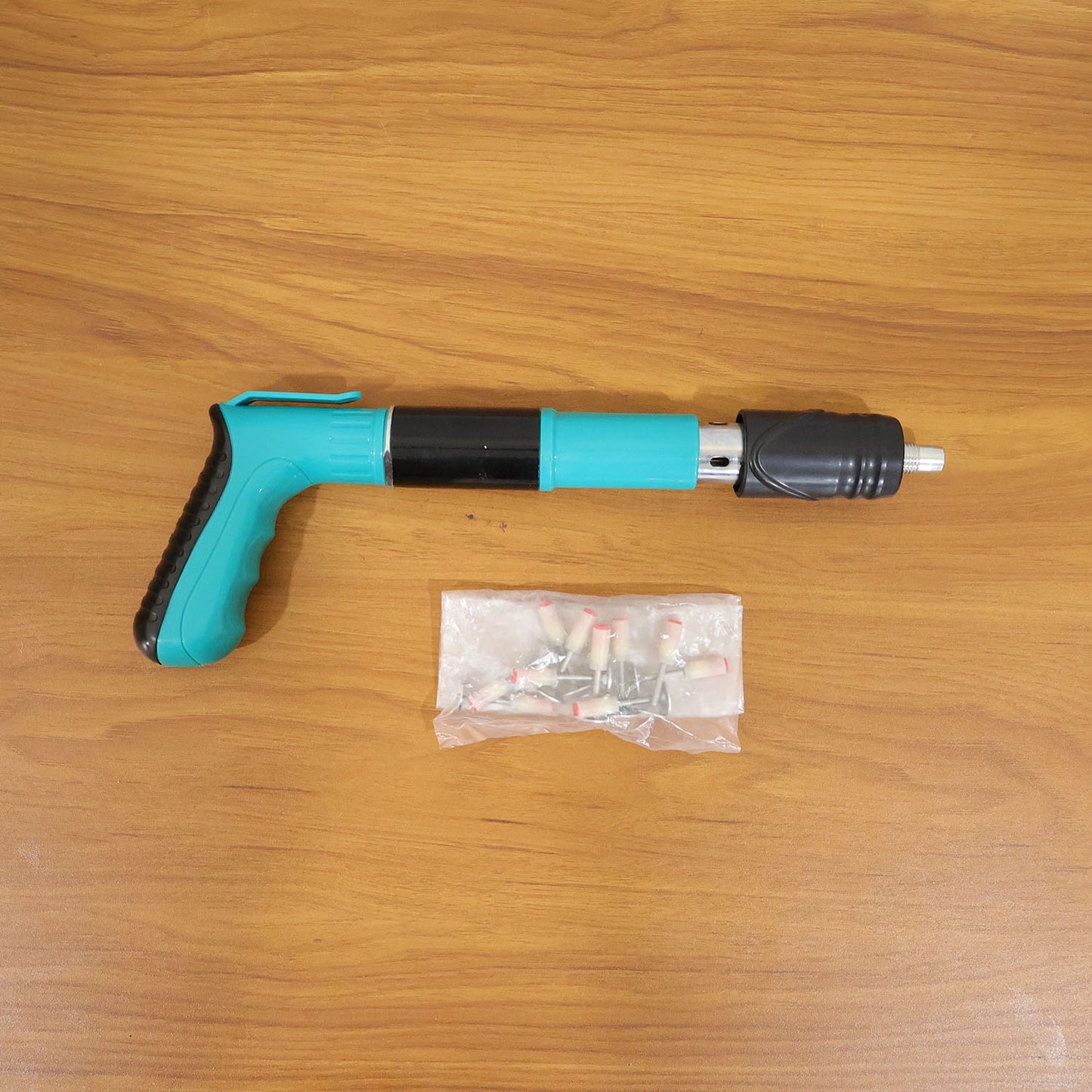 Wukusy manual wall fastening tool nail gun with steel nails set, showing the compact handheld device and included nails.