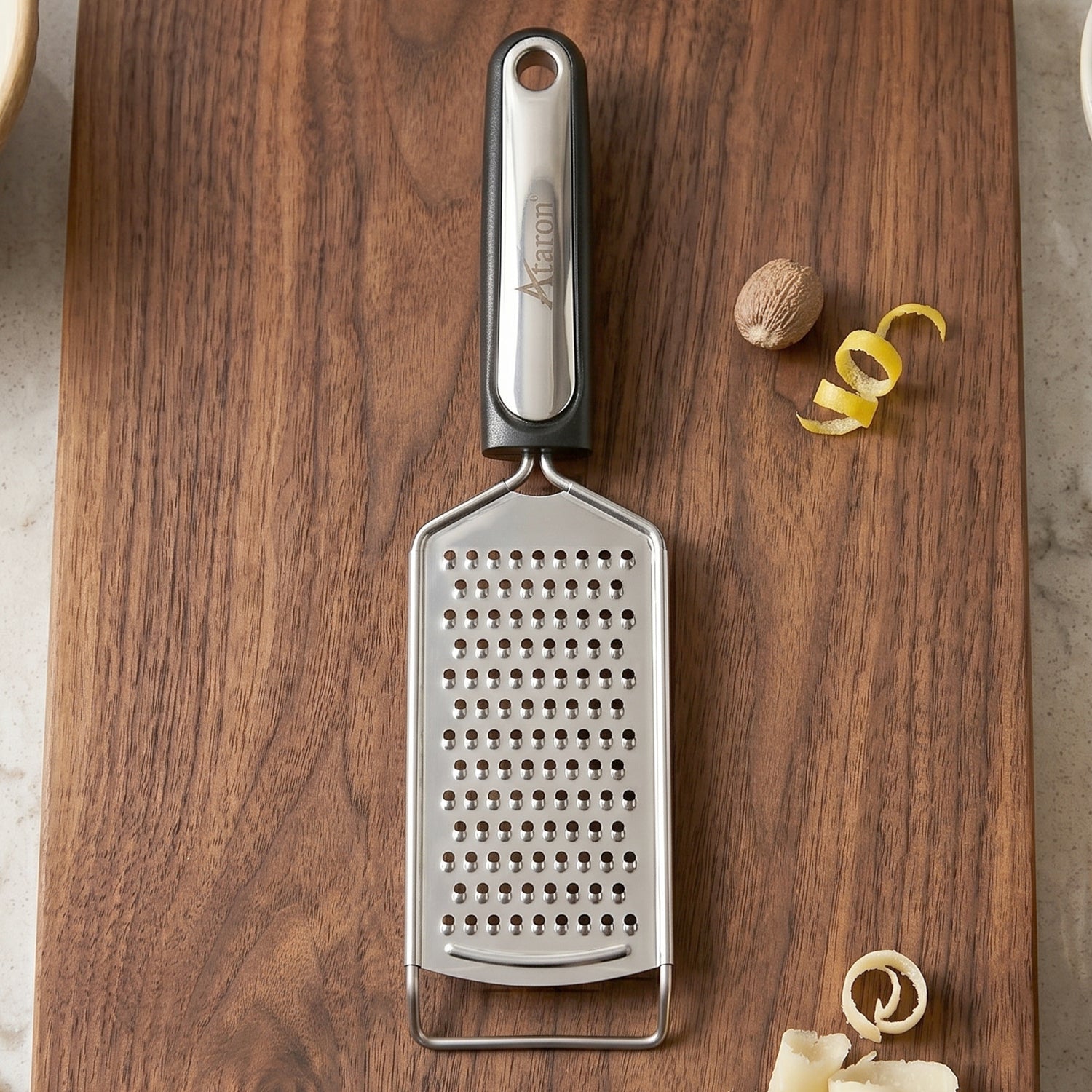 Wukusy SS slim cheese grater with plastic handle, ideal for vegetables and lemon zest, shown with grated produce.