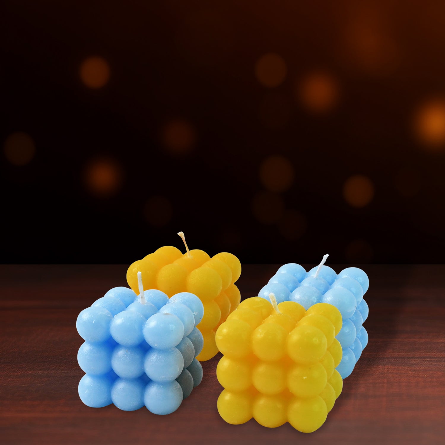 Four colorful cube-shaped wax candles for home decor by Wukusy, arranged on a neutral surface.