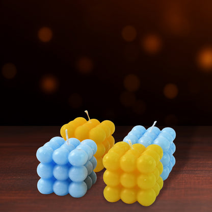 Four colorful cube-shaped wax candles for home decor by Wukusy, arranged on a neutral surface.